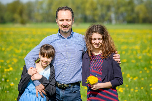 istock Happy father standing with his daughters in a meadow 1494261126