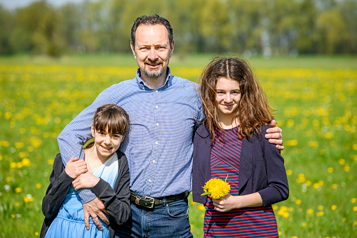 Happy father standing with his daughters in a meadow