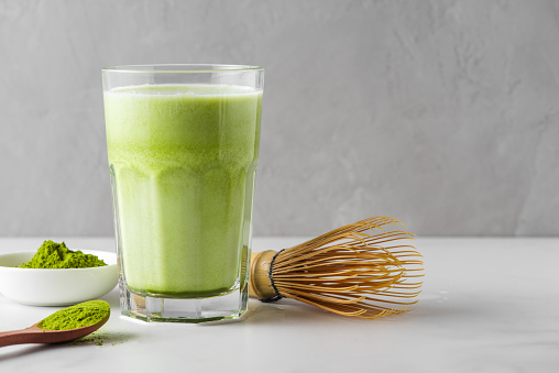 Matcha green tea iced latte with matcha powder and bamboo whisk. Cold refreshment summer drink. Vegan food