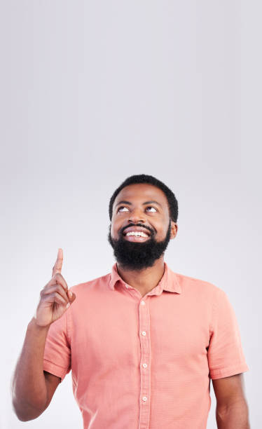 istock Point, mockup space and black man looking up with hand gesture for product placement, advertising and sign. Happy, studio and male smile on white background pointing for choice, branding and showing 1494262272