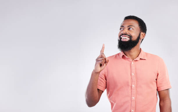 istock Point, studio and black man with mockup space and hand gesture for product placement, advertising and sign. Happy, smile and male thinking on white background pointing up for choice, branding or show 1494262281