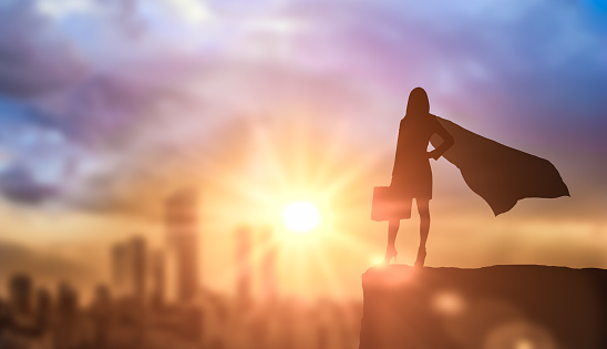 silhouette of super business woman on sunset city background. businesswoman in superhero cape looks at with skyscrapers. women building career in business, politics and life