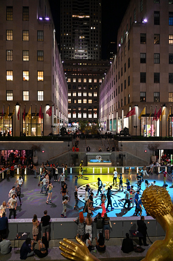 New York, USA, 13. April 2023 - Flipper's Roller Boogie Palace event at the rink of the Rockefeller Center plaza, with the golden Prometheus in Manhattan New York, USA in the background.