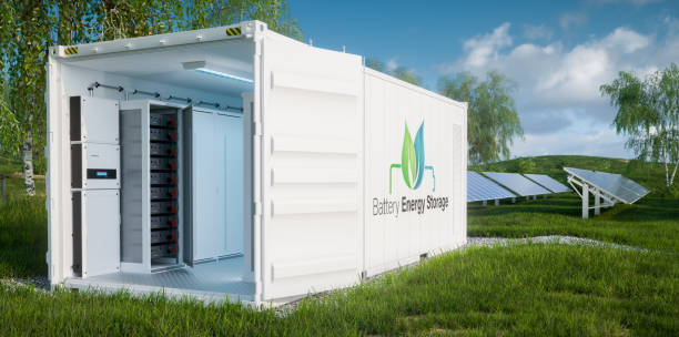 Close up view of the battery modules for energy storage inside open industrial container on a lush lawn with a photovoltaic power plant in the background. 3d rendering. Close up view of the battery modules for energy storage inside open industrial container on a lush lawn with a photovoltaic power plant in the background. 3d rendering. battery storage stock pictures, royalty-free photos & images