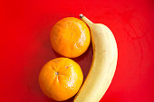 Tangerines and Banana on Vibrant Red Background Close-Up