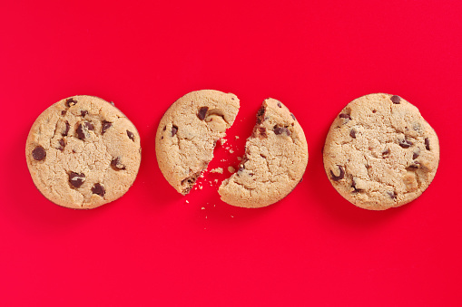 Chocolate chip cookies with two half on red background, top view