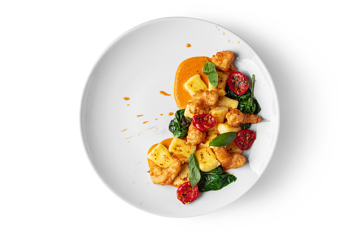 Shrimps in batter with tomatoes, cheese, basil, spinach and sauce in a plate on a white background