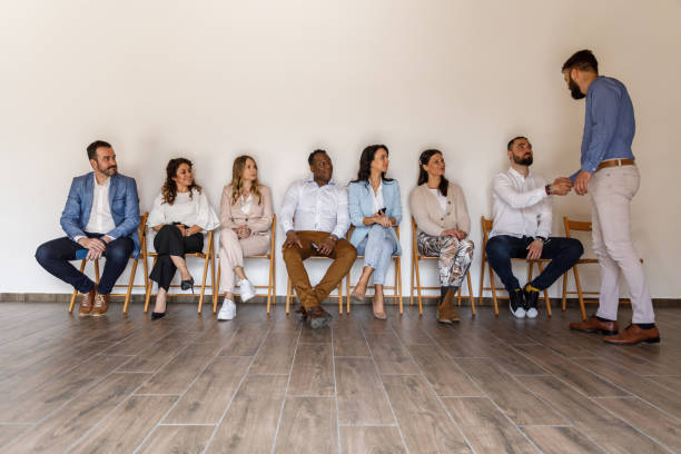 biznesmen ściskający dłoń kandydatom czekającym w kolejce na rozmowę kwalifikacyjną - unemployment waiting in line waiting room interview zdjęcia i obrazy z banku zdjęć