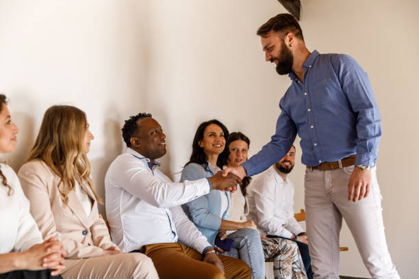 biznesmen ściskający dłoń kandydatom czekającym w kolejce na rozmowę kwalifikacyjną - unemployment waiting in line waiting room interview zdjęcia i obrazy z banku zdjęć