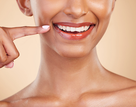 Closeup, smile and mouth of woman in studio for dental, cleaning and hygiene treatment on brown background. Zoom, lips and teeth whitening for happy girl smiling after veneers, braces or oral care
