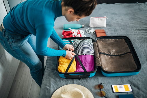 Young woman packing suitcase for travel.