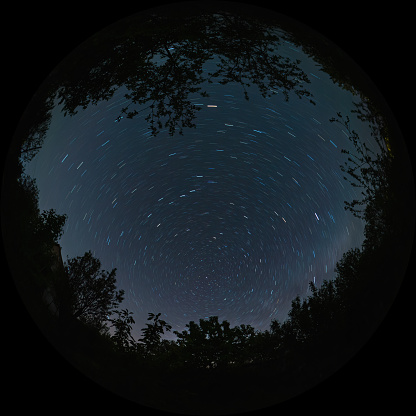 Star trails in the form of lines in the night sky with a long exposure. The movement of stars around the North Celestial Pole of the polar star. The photo was taken through a wide-angle circular fisheye lens, fulldome format