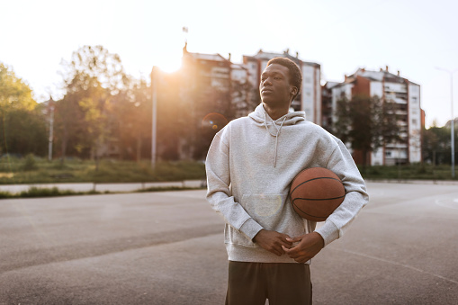 Outdoor portrait of young basketball player with basketball in hands