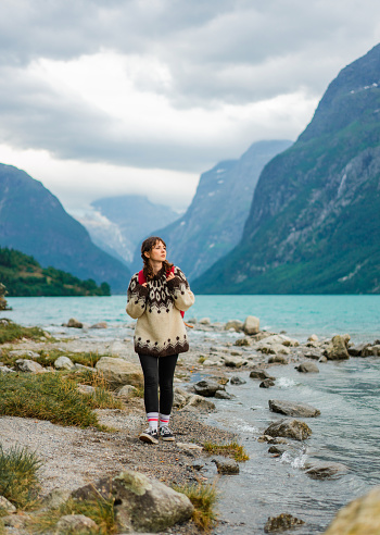 Young Caucasian woman with backpack hiking near  the lake in Norway
