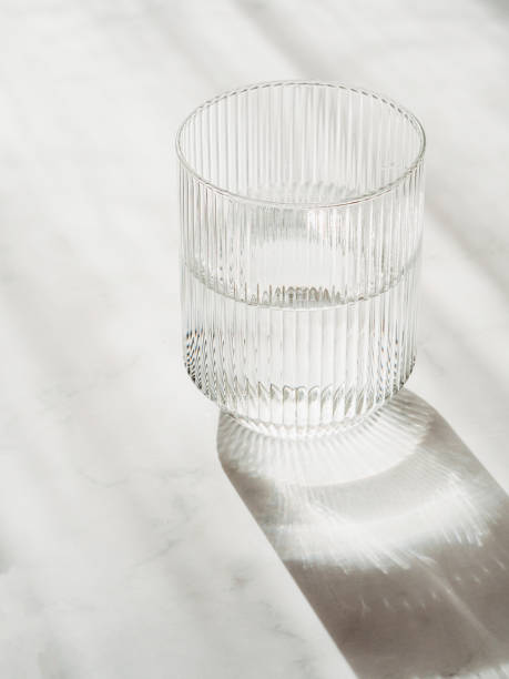 istock Glass with clean clear water and shadows stands on a white table 1494287074