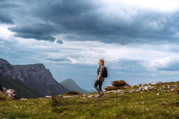 istock Woman hiking on mountain against cloudy sky 1494287194