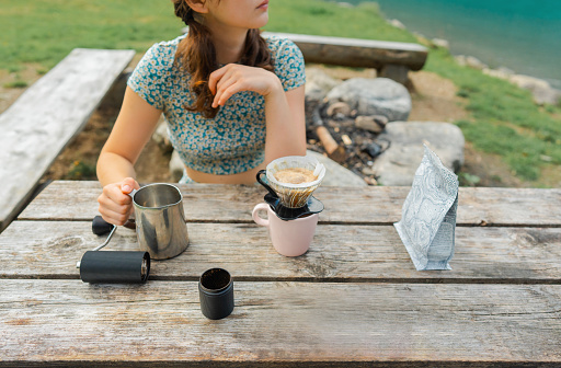 Young Caucasian woman brewing drip coffee in nature