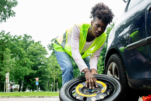 Young woman is changing a car tire