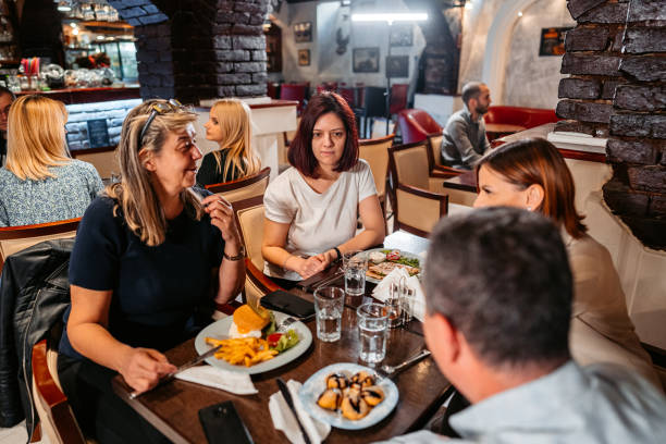 istock Group Of Mid Adults Eating And Drinking In A Restaurant 1494290018