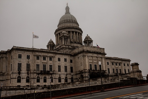 A white, multi-story building with several flags waving on a flagpole atop its roof