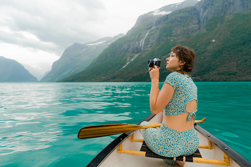 Young woman photographing while canoeing on the lake in Norway