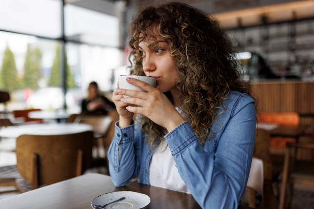 jeune femme buvant un café dans un café - coffee shop coffee break coffee cup holding photos et images de collection
