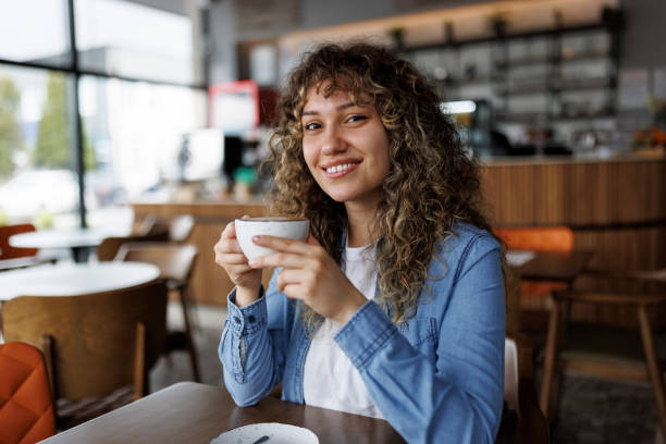 istock Young smiling woman drinking coffee in a cafe 1494295690