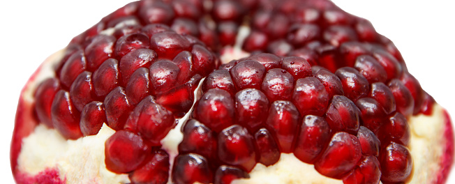 Sweet, ripe peeled red pomegranate. Sections and grains of a large tasty grenade on a white background are clearly visible