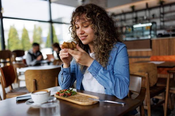 joven mujer sonriente disfrutando de un desayuno saludable en un café - salad breakfast cooked eggs fotografías e imágenes de stock