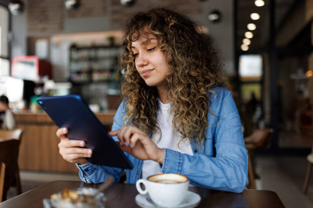 istock Young smiling woman using digital tablet and enjoying coffee drink at a cafe 1494295963