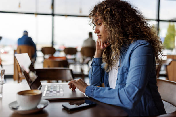 istock Young woman working on laptop at a cafe 1494296060