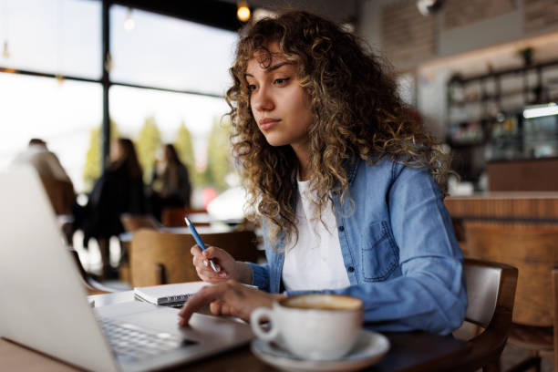 istock Attractive young woman working on laptop and taking notes at a cafe 1494296145