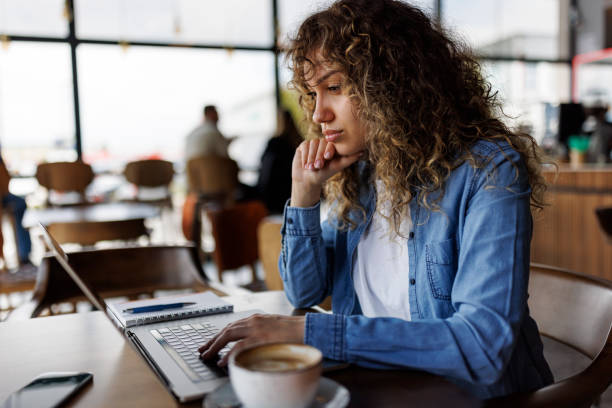 istock Young serious woman working on laptop at a cafe 1494296251