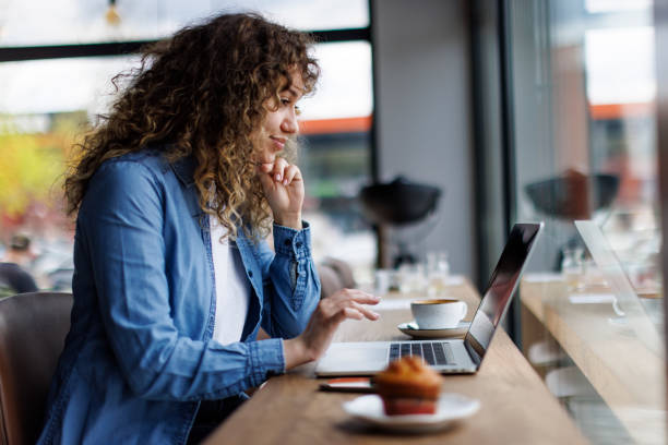 istock Young woman working on laptop at a cafe 1494296493