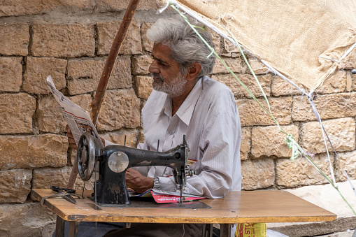 Jaisalmer Rajasthan India march 24, 2023: street tailor reads newspaper