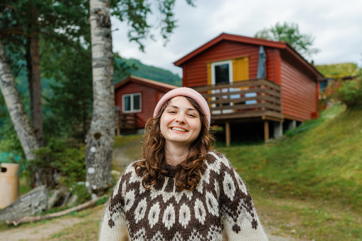 Young Caucasian woman in knitted sweater standing in Norwegian countryside