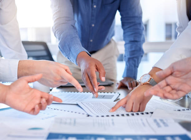 istock Documents, teamwork and hands pointing in office for planning sales strategy. Cooperation, collaboration and group of business people with report, paperwork or information in meeting for research. 1494298042
