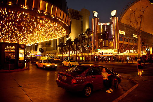 Old lady geting out of car in vibrant and illuminated Las Vegas. Nightlife near Fremont street. Summer 2010.