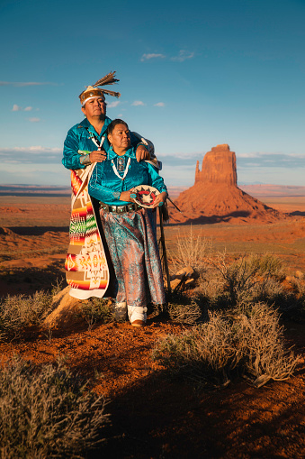 Portrait of a Navajo couple standing in front of the famous view in Monument Valley Tribal Park, Arizona.