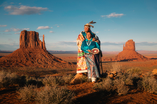 Portrait of a Navajo couple standing in front of the famous view in Monument Valley Tribal Park, Arizona.