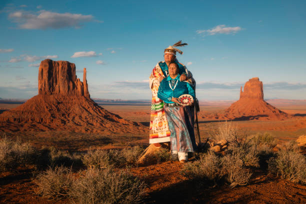 Navajo Couple in Monument Valley Portrait of a Navajo couple standing in front of the famous view in Monument Valley Tribal Park, Arizona. west mitten stock pictures, royalty-free photos & images