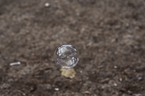 A person stands outdoors and throws a glass ball up into the air, their arms extended in a throwing motion