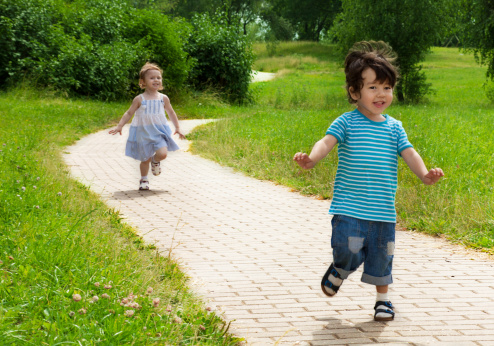 little girl chasing cute little boy in the park