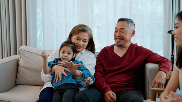 istock Two Elderly Asian People Playing with Granddaughter while Talking with Son. 1494311535