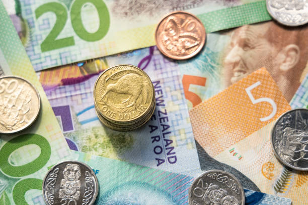 New Zealand currency close-up A stack of one dollar coins, and other New Zealand coins on top of a collection of different banknotes. new zealand dollar photos stock pictures, royalty-free photos & images