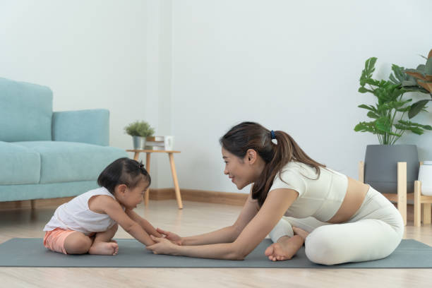 мама и дочь вместе занимаются йогой в комнате дома. азиатская женщина делает зарядку по утрам. баланс, медитация, релаксация, спокойствие, х� - yoga challenge for 3 стоковые фото и изображения