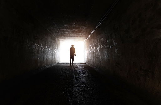 Sewer tunnel worker examines sewer system damage and wastewater leakage.