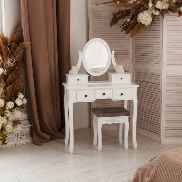 White dressing table with oval mirror and chair is part of cosy interior of beautiful  bedroom stock photo