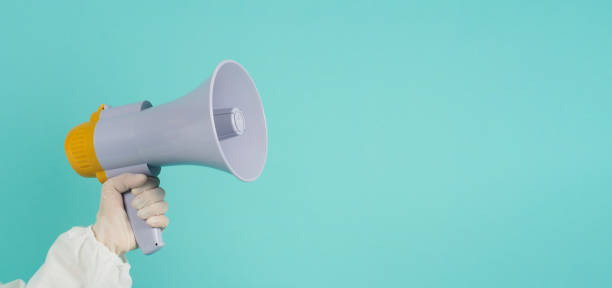 istock Hand is hold megaphone and wear PPE suit on green mint color 1494317639