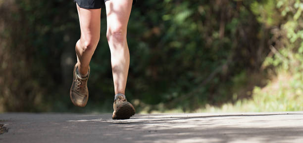 istock Woman runs in the forest on a rural asphalt road 1494318496